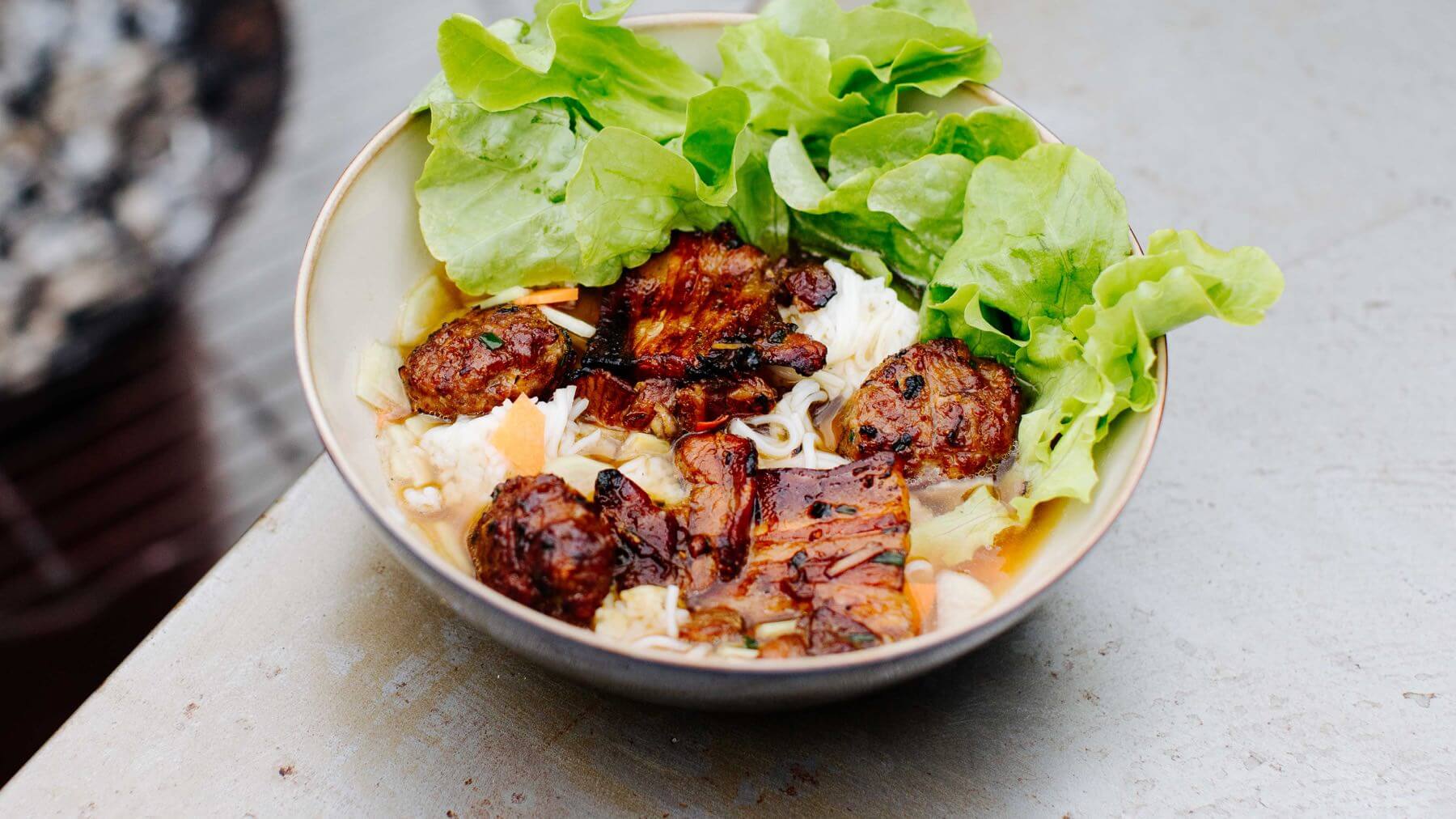 Gegrilltes Schweinefleisch - Bun Cha: Bún Chả ist Hanois ikonisches Streetfood: kleine gegrillte Frikadellen aus Schweinefleisch, gewürzt mit Karamellsauce und Schnittlauch, über Holzkohle gegrillt und serviert mit Reisnudeln, frischen Kräutern...