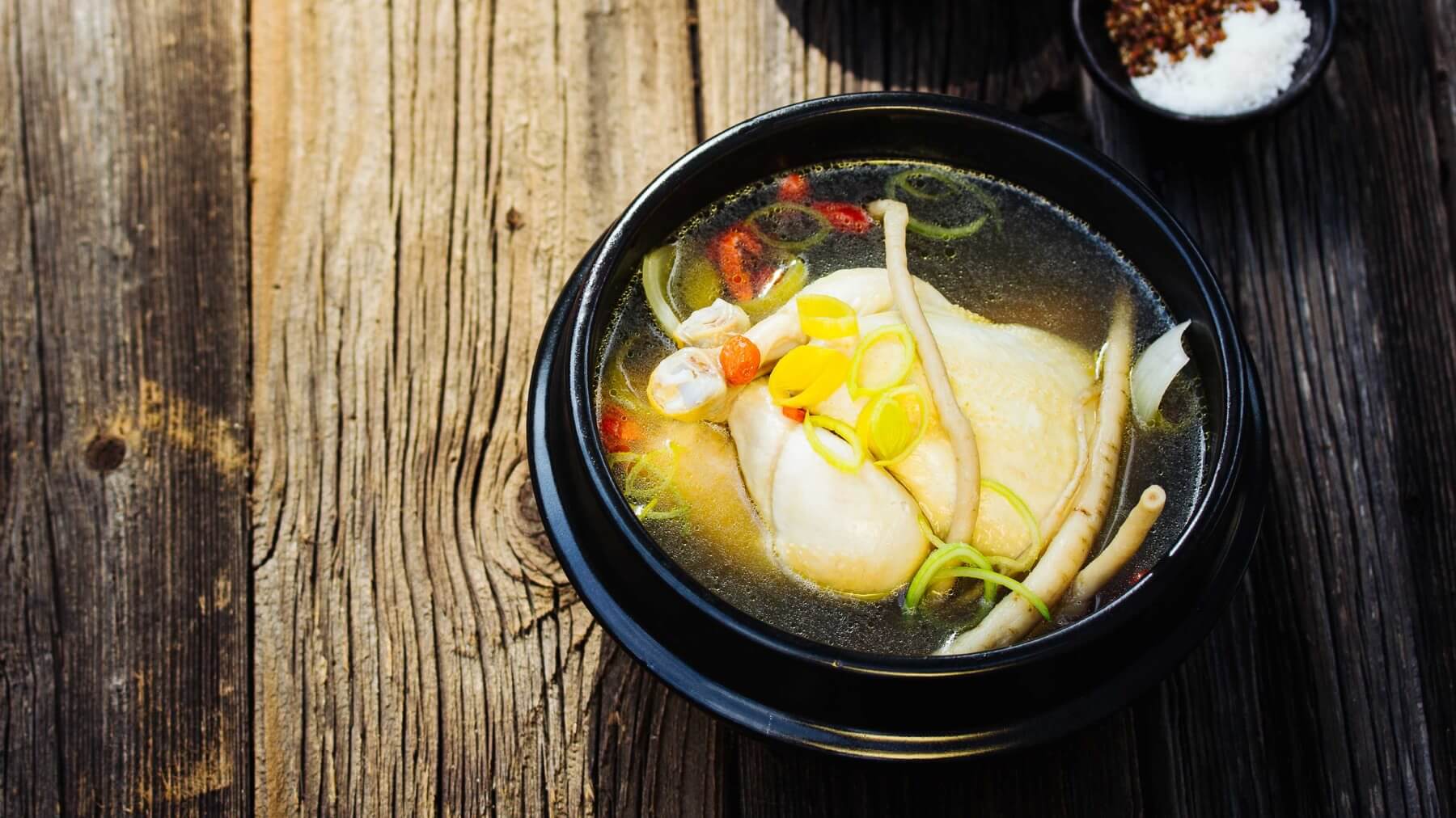 Koreanische Hühnersuppe mit Ginseng - Samgyetang: Samgyetang ist Koreas Antwort auf Sommerhitze: ein zartes Hähnchen, gefüllt mit süßem Reis und Knoblauch, langsam gekocht in einer Brühe mit Ginseng und roten Datteln. An den heißesten Tagen des...