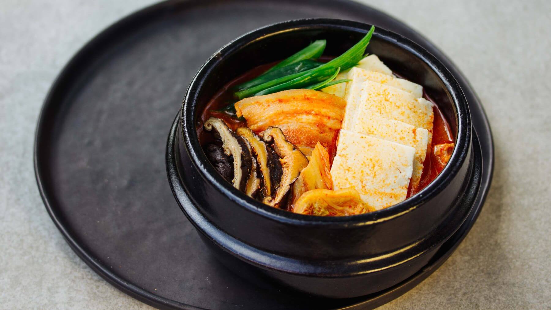 Koreanischer Kimchi Eintopf - Kimchi Jjigae: Kimchi Jjigae ist echtes Korean Soulfood – und hier spielt Kimchi endlich die Hauptrolle! Zusammen mit Schweinebauch, Brühe und viel Zeit zum Köcheln entsteht ein herzhaft-würziger Eintopf, der wärmt,...