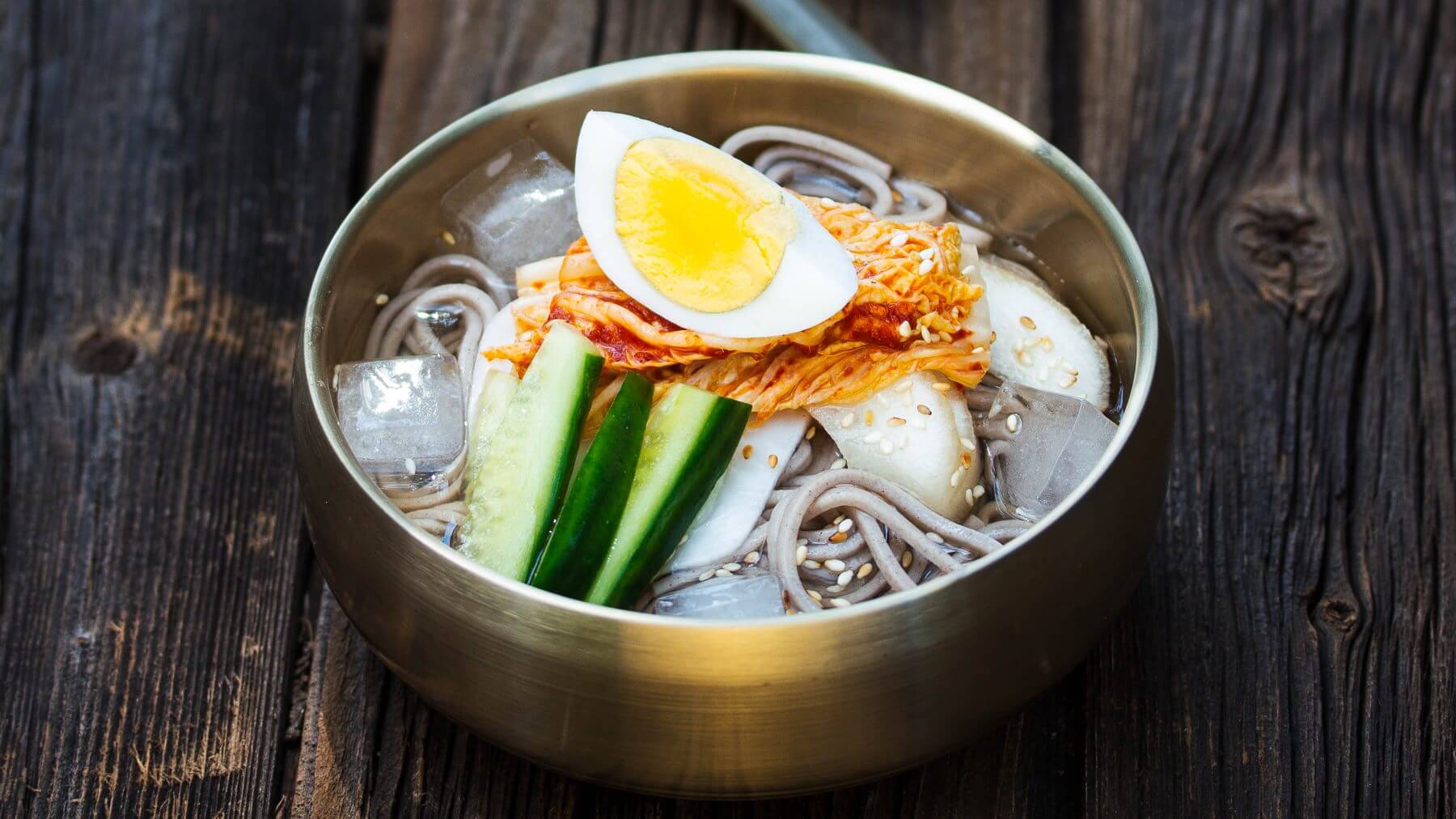 Sommerliche Nudelsuppe aus Korea - Mul-Naengmyeon: An heißen Sommertagen sorgt Mul-naengmyeon für die perfekte Erfrischung – eine eiskalte koreanische Nudelsuppe, die mit Buchweizennudeln, klarer Fleischbrühe, Gurkenstreifen, asiatischer Birne,...