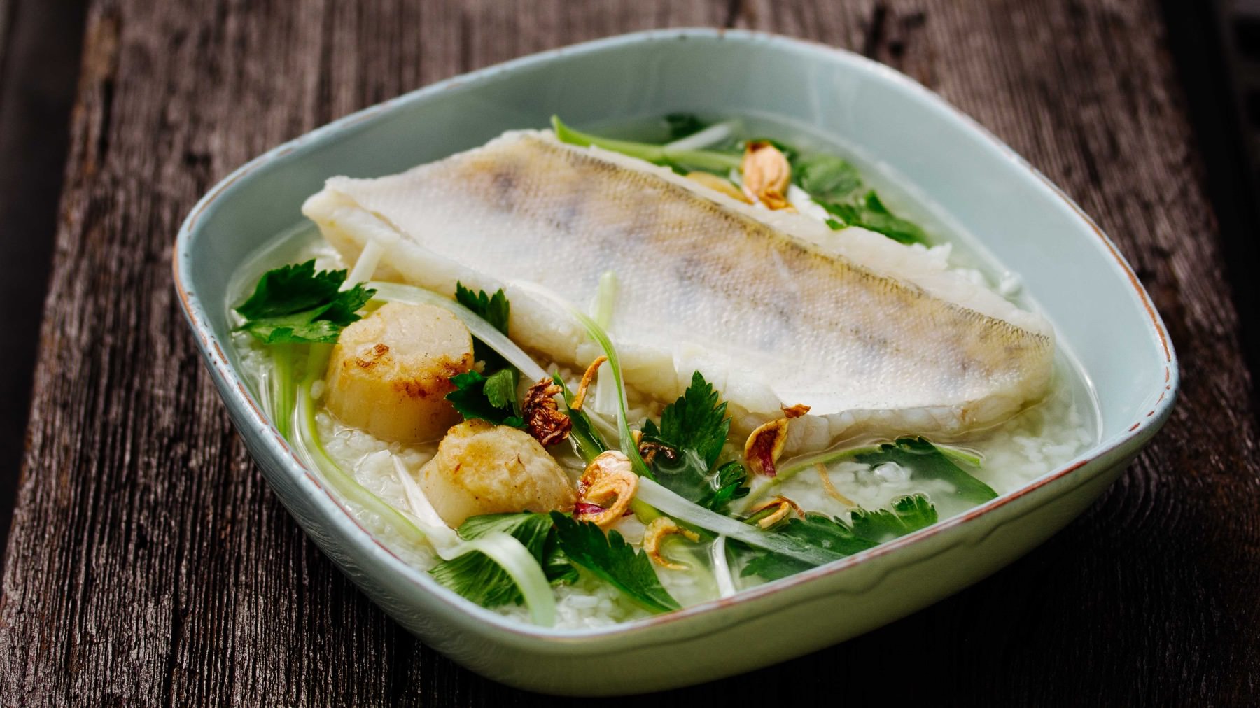 Reissuppe mit Wolfsbarsch - Khao Tom Pla: Khao Tom Pla – Reissuppe mit Fisch – ist ein einfaches, wärmendes Gericht mit überraschender Raffinesse. 🍚 Entlang der Thanon Chan Road in Bangkok, nahe dem Fischmarkt Saphan Pla, servieren Straßenküchen...