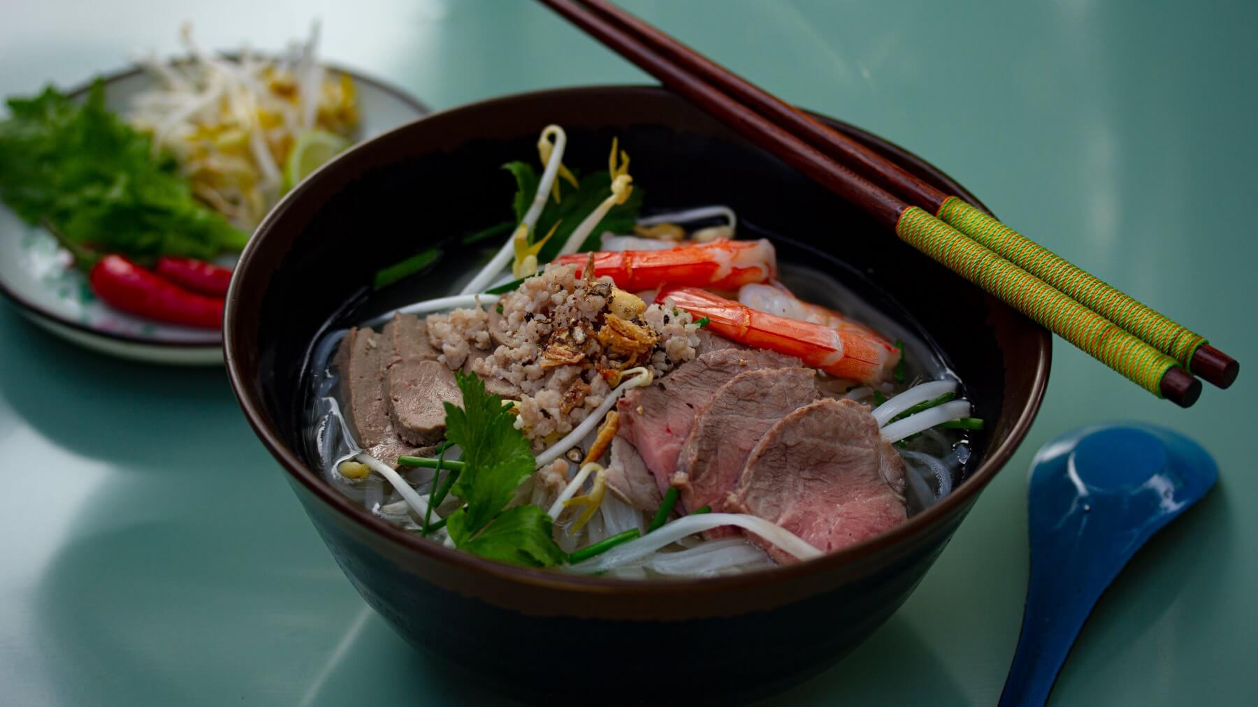 Hu Tieu Nam Vang - Nudelsuppe mit Shrimps und Schweinefleisch: Hu Tieu Nam Vang steht für eine Suppe mit Khmer-Wurzeln - Nam Vang heißt Phnom Penh auf vietnamesisch - die über Kambodscha ihren Weg nach Südvietnam fand. 🍜 Die Brühe wird...
