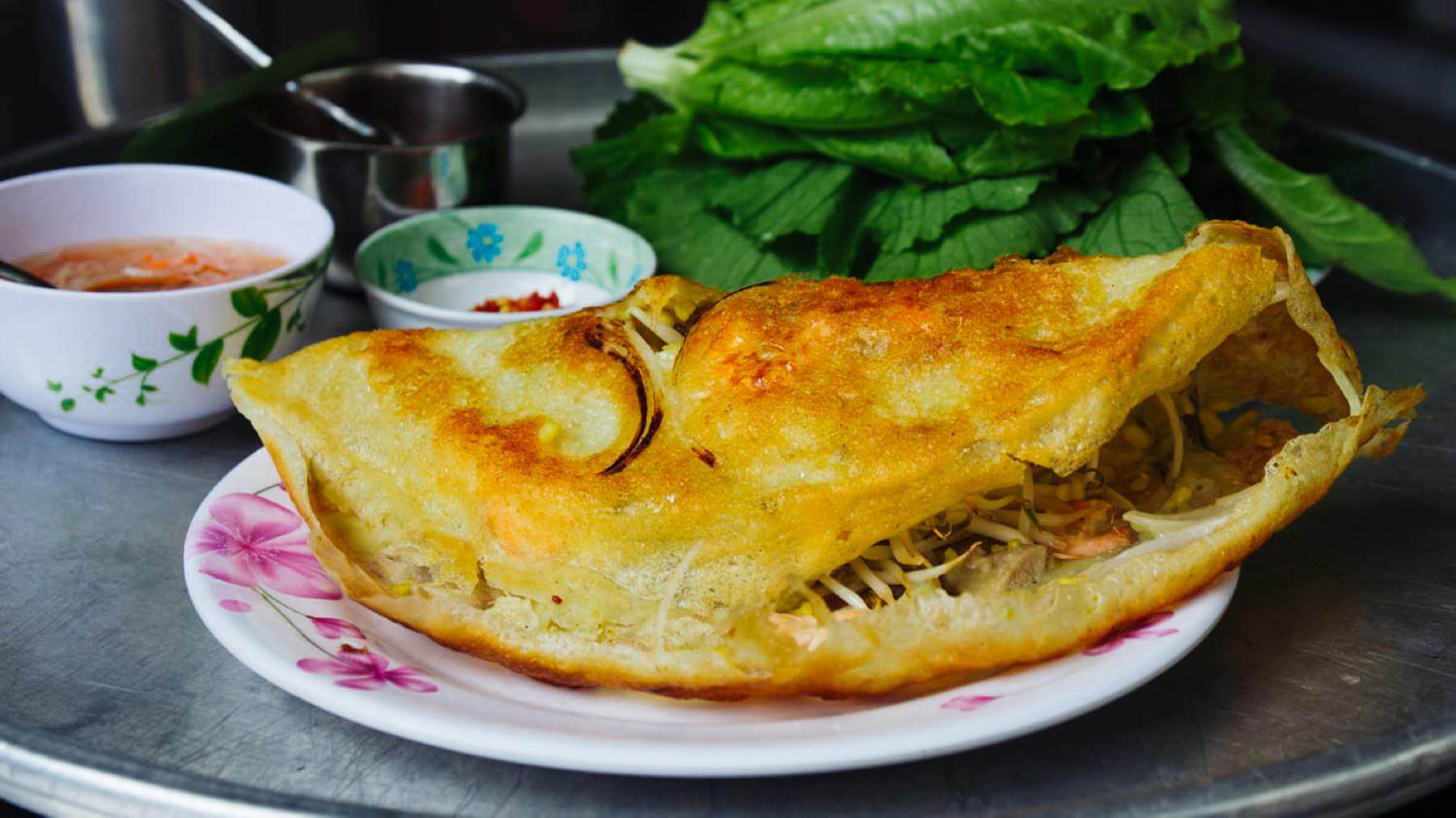 Banh Xeo - Vietnamesische Crêpes aus Hoi An: Bánh Xèo sind dünne, knusprige Crêpes aus Reismehl, die durch Kurkuma ihre goldgelbe Farbe erhalten. 🥞 Gefüllt mit Schweinefleisch und Garnelen, werden sie wie Sommerrollen in Reispapier gewickelt, in...