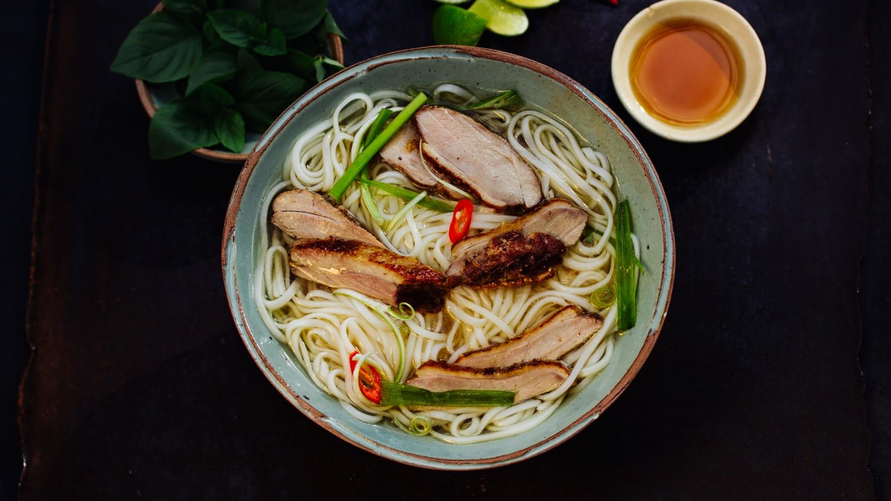 Vietnamesische Nudelsuppe mit Ente: Pho Vit ist eine aromatische Reisnudelsuppe mit knuspriger Ente, die in einer kräftigen Brühe serviert wird – herzhaft, klar und voller Tiefe. 🍜 Unser erstes Mal: eine kleine Straßenküche im Süden Hanois mit...